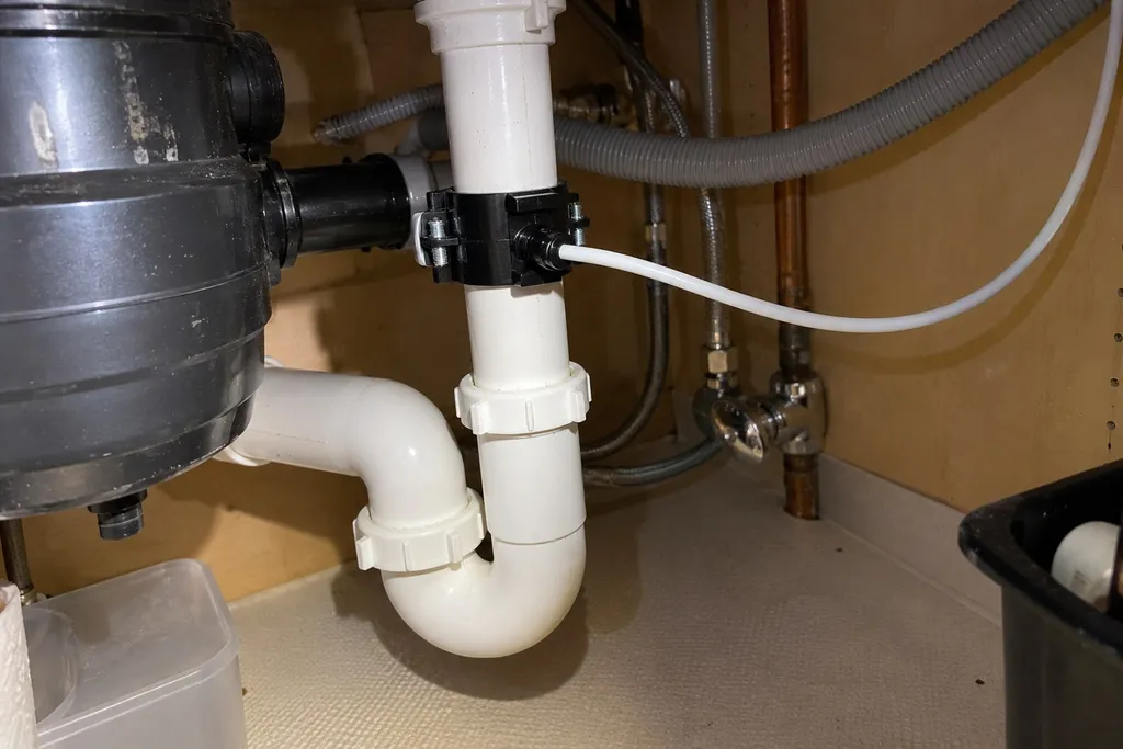 RO drain saddle clamped on the sink tailpiece above the trap with tubing run downhill